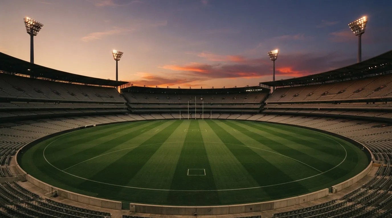 An empty football stadium with floodlight masts at dusk