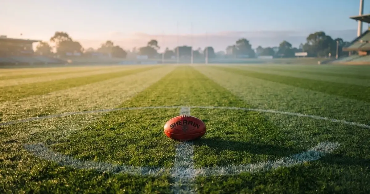 A ball on the centre spot of a grass pitch in morning light