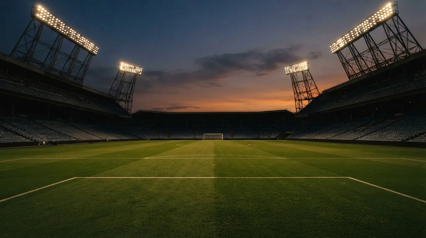An empty football stadium with floodlight masts at dusk