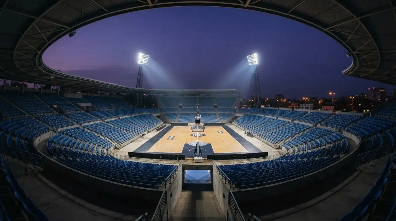 An empty football stadium with floodlight masts at dusk