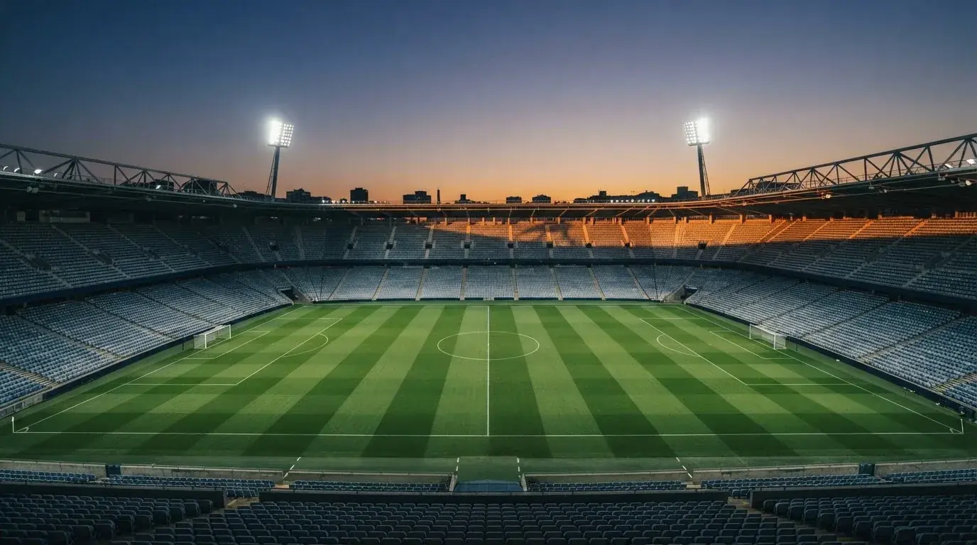 An empty football stadium with floodlight masts at dusk