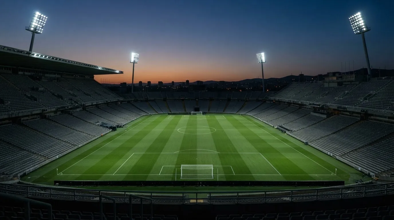 An empty football stadium with floodlight masts at dusk