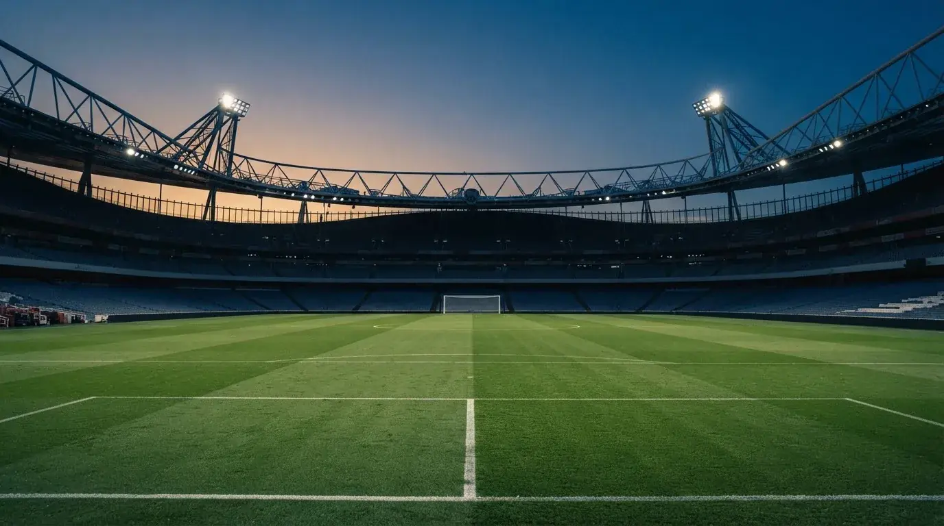 An empty football stadium with floodlight masts at dusk