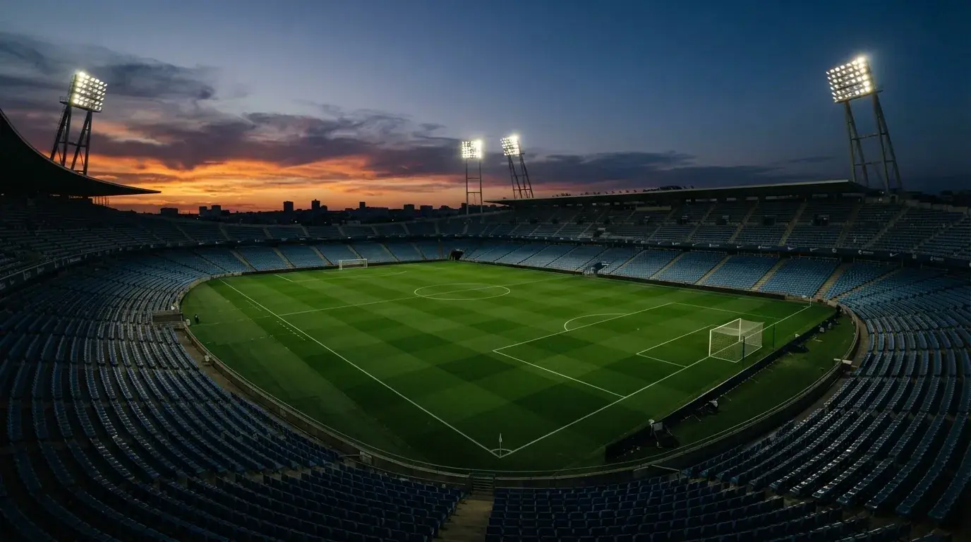An empty football stadium with floodlight masts at dusk