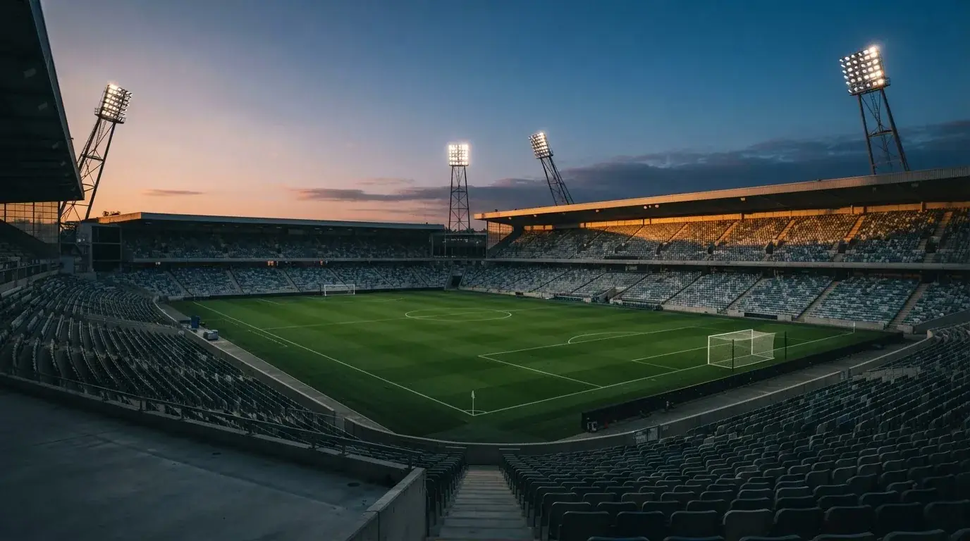 An empty football stadium with floodlight masts at dusk