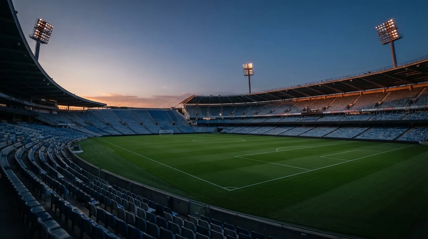 An empty football stadium with floodlight masts at dusk