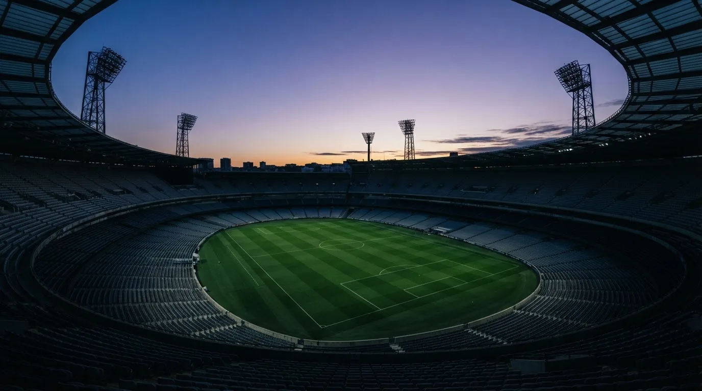 An empty football stadium with floodlight masts at dusk