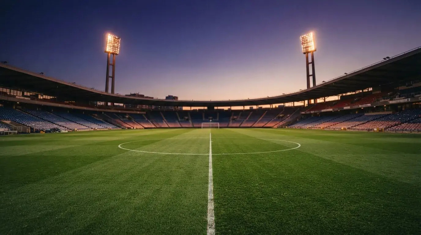 An empty football stadium with floodlight masts at dusk