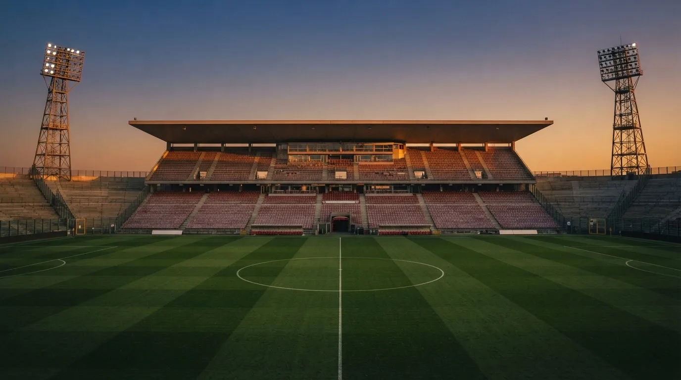 An empty football stadium with floodlight masts at dusk