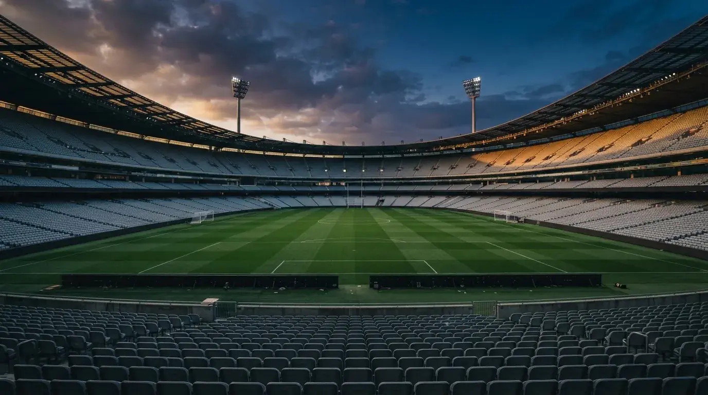 An empty football stadium with floodlight masts at dusk