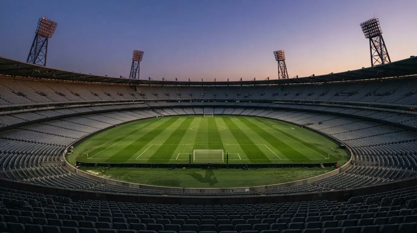 An empty football stadium with floodlight masts at dusk