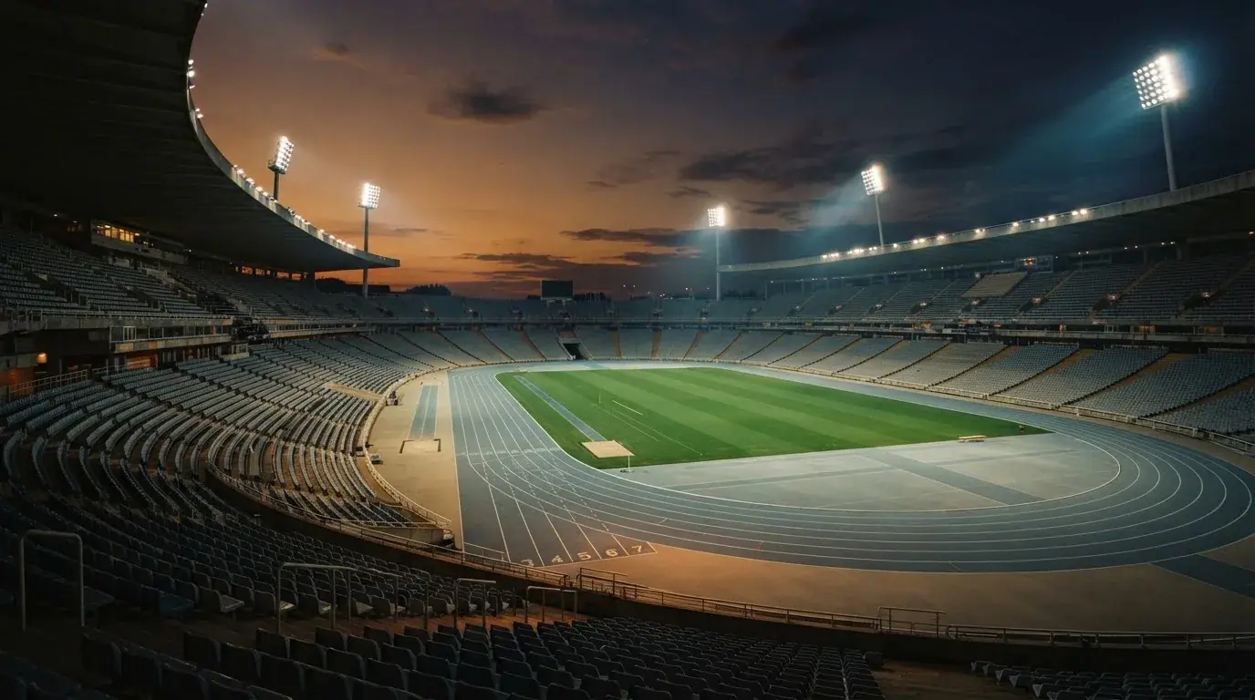 An empty football stadium with floodlight masts at dusk