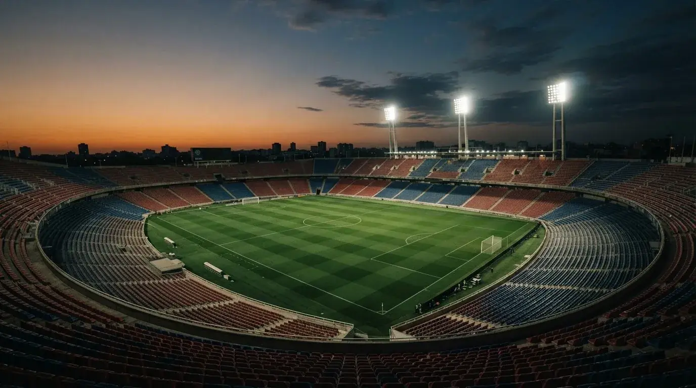 An empty football stadium with floodlight masts at dusk