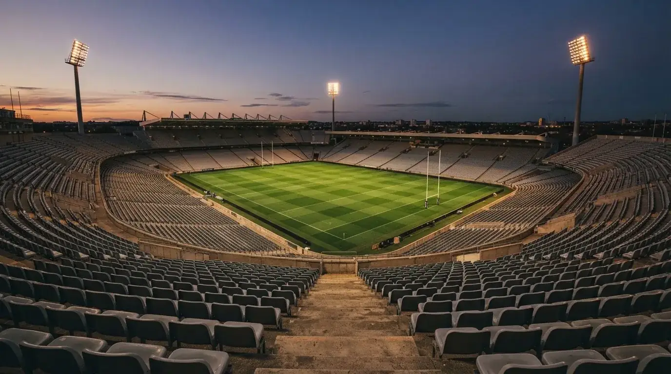 An empty football stadium with floodlight masts at dusk