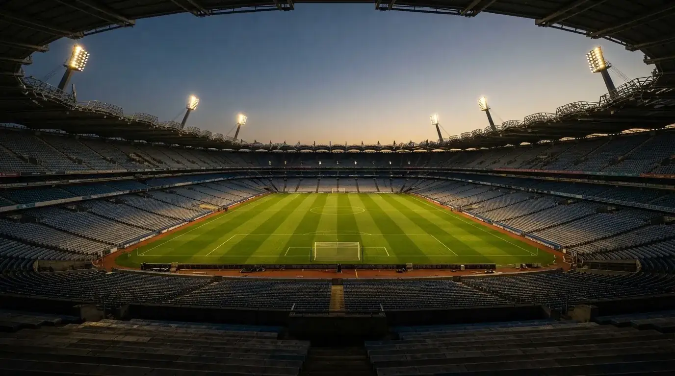 An empty football stadium with floodlight masts at dusk