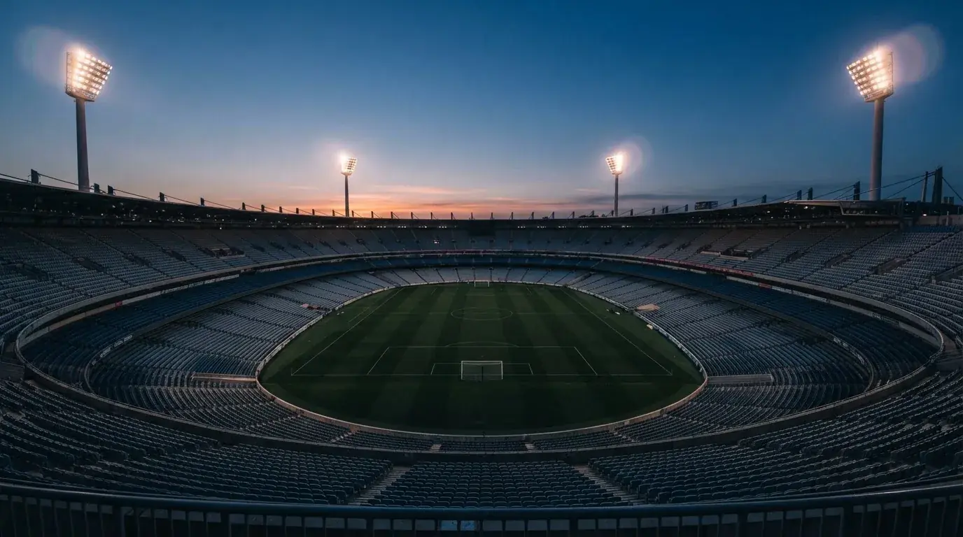 An empty football stadium with floodlight masts at dusk