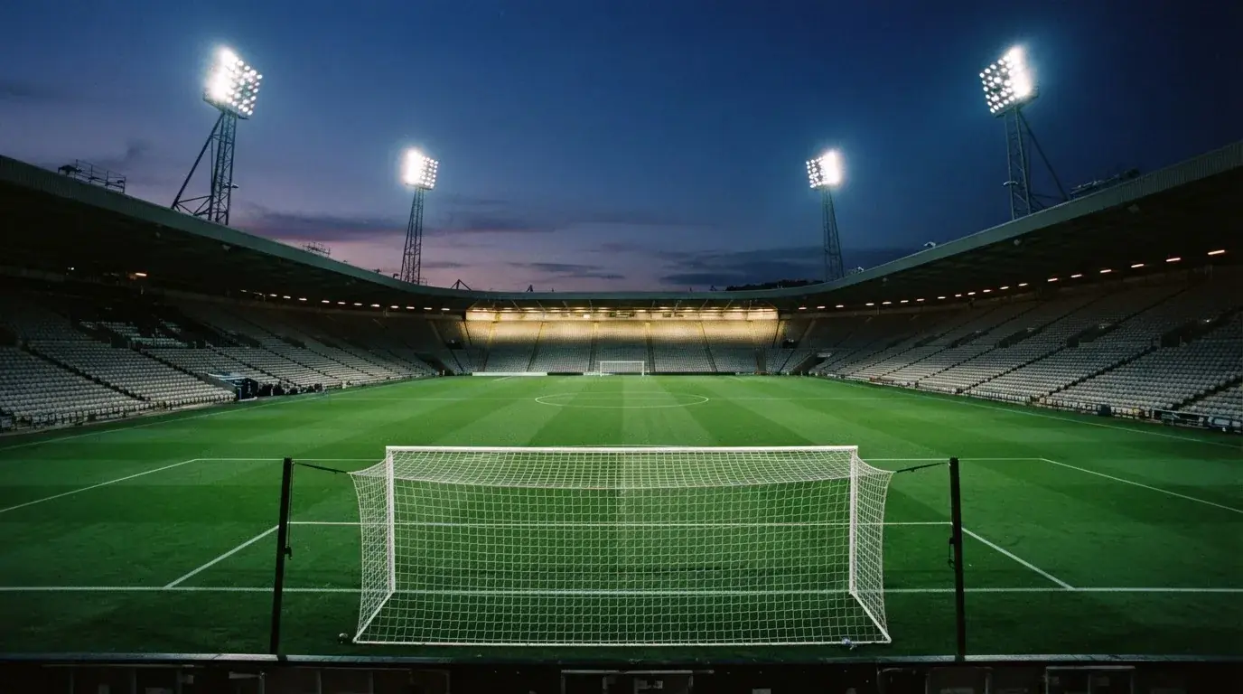 An empty football stadium with floodlight masts at dusk