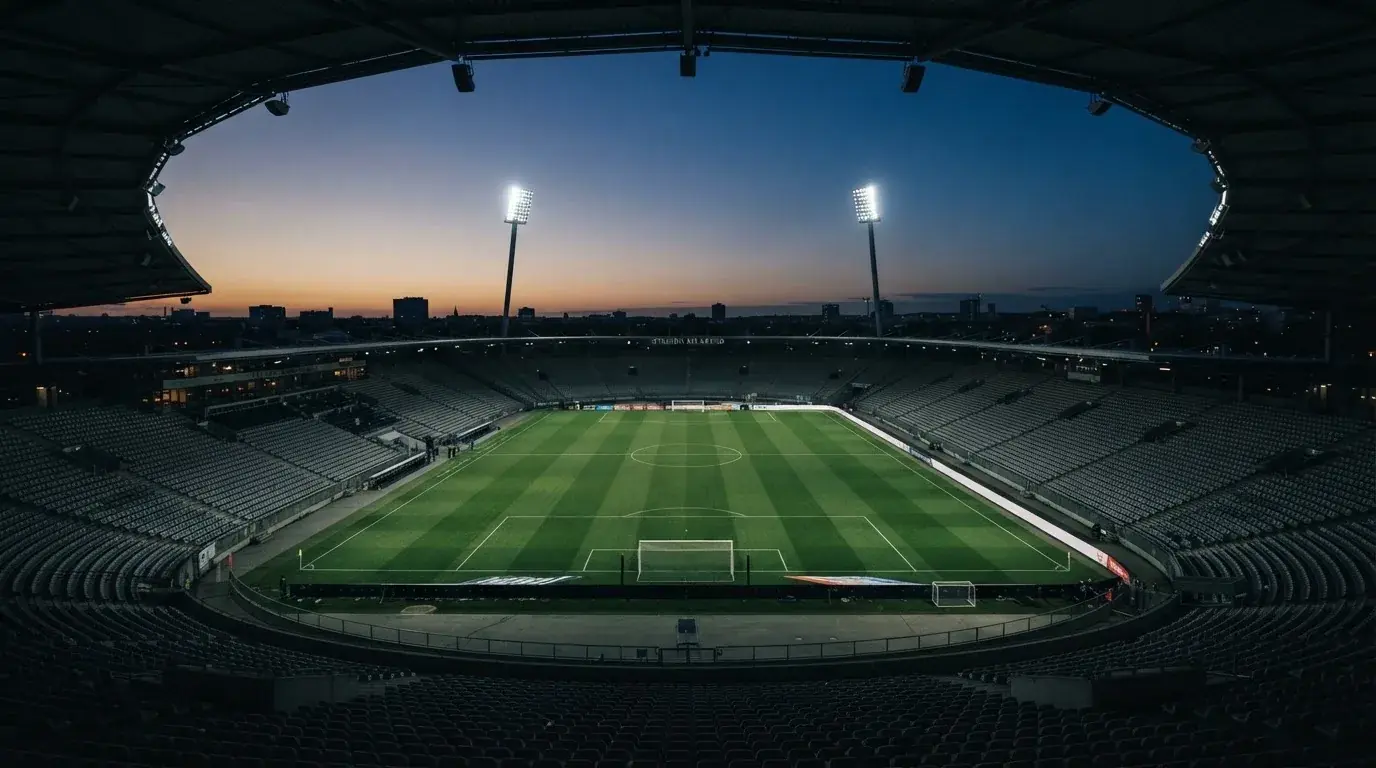 An empty football stadium with floodlight masts at dusk